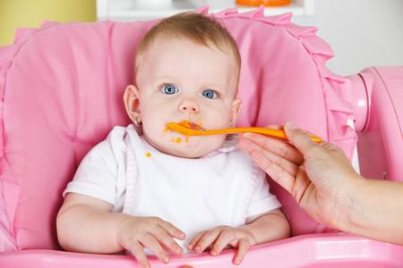 bambina-mangia-seggiolone-©-Kicsiicsi-_-Dreamstime.com---Baby-Eating-Carrot-Photo